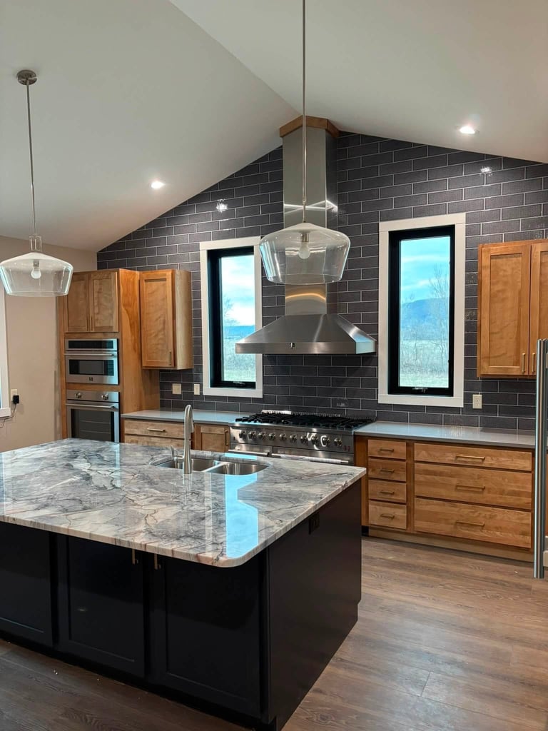 Modern kitchen with dark tile backsplash, marble island, black range hood, wood cabinetry, and recessed lighting