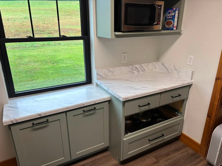 RV kitchen area with window, cabinets, stovetop, and mattress on counter space