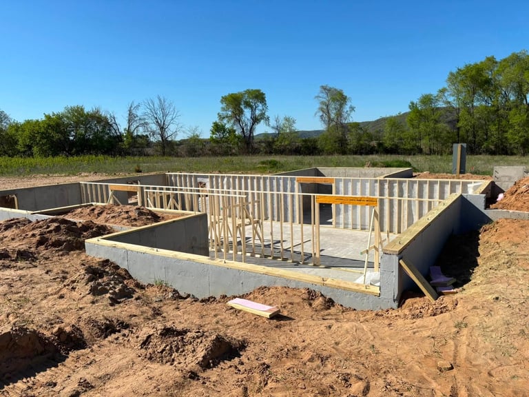 Construction site with concrete foundation and wooden framing for a new building structure under development in a rural setting