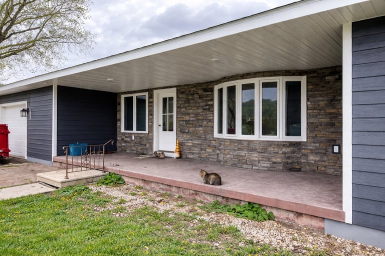 Modern brick house with covered patio, large windows, and attached garage on landscaped yard