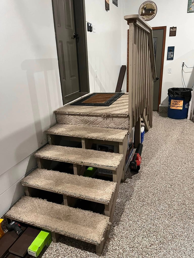 Basement staircase with concrete steps and metal railing leading up to closed doors