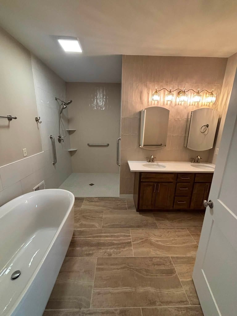 Modern bathroom with freestanding tub on left, double vanity sink with mirrors and lighting on right, walk-in shower with glass enclosure in back
