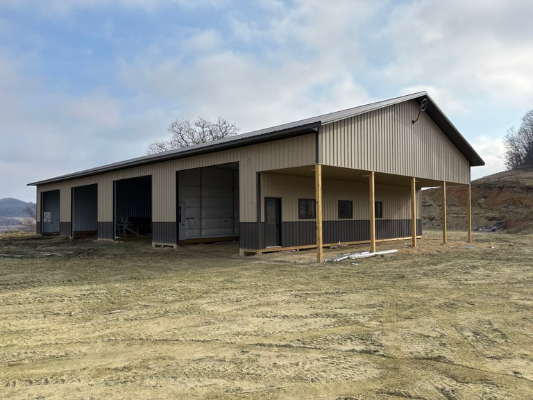 Large metal-sided barn with open lean-to structure in sparse rural landscape